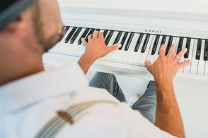 Pianist Josef Barnickel an einem weißen Klavier