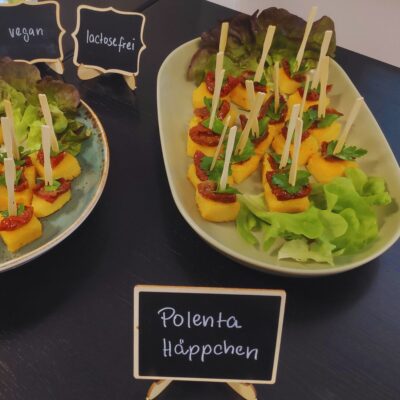 Fingerfood mit gebratener Polenta, getrockneten Tomaten und Kräutern