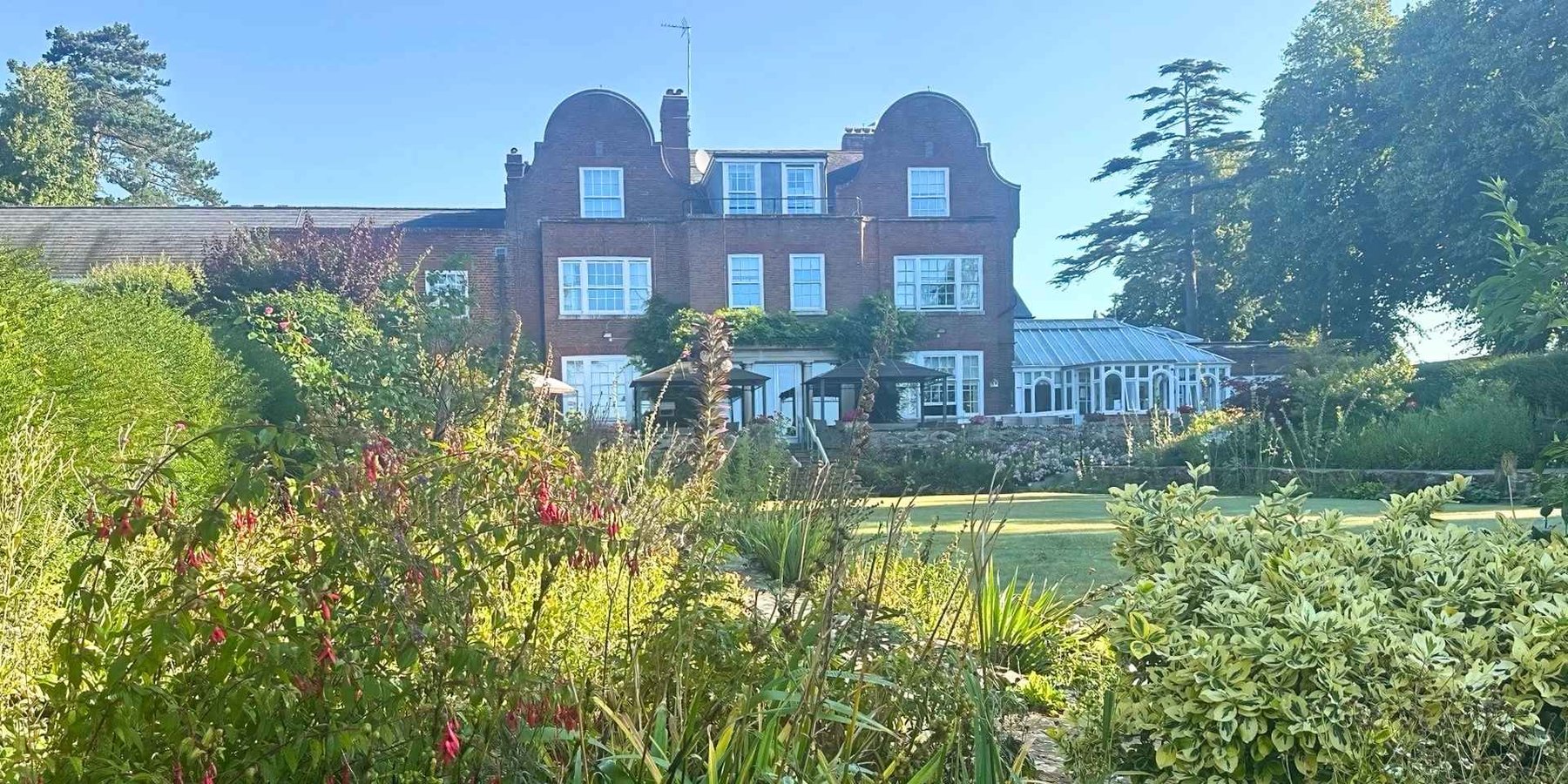 Red-brick exterior of this care home in Lowestoft beyond colourful formal gardens