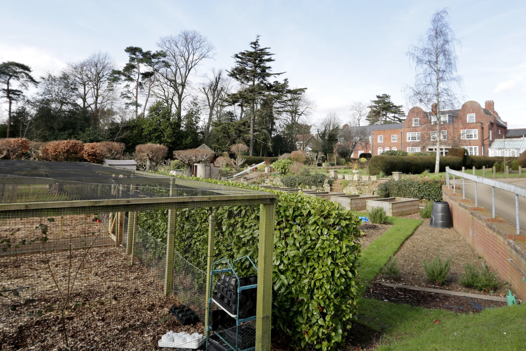 Garden growing area with raised beds and the red-brick home beyond