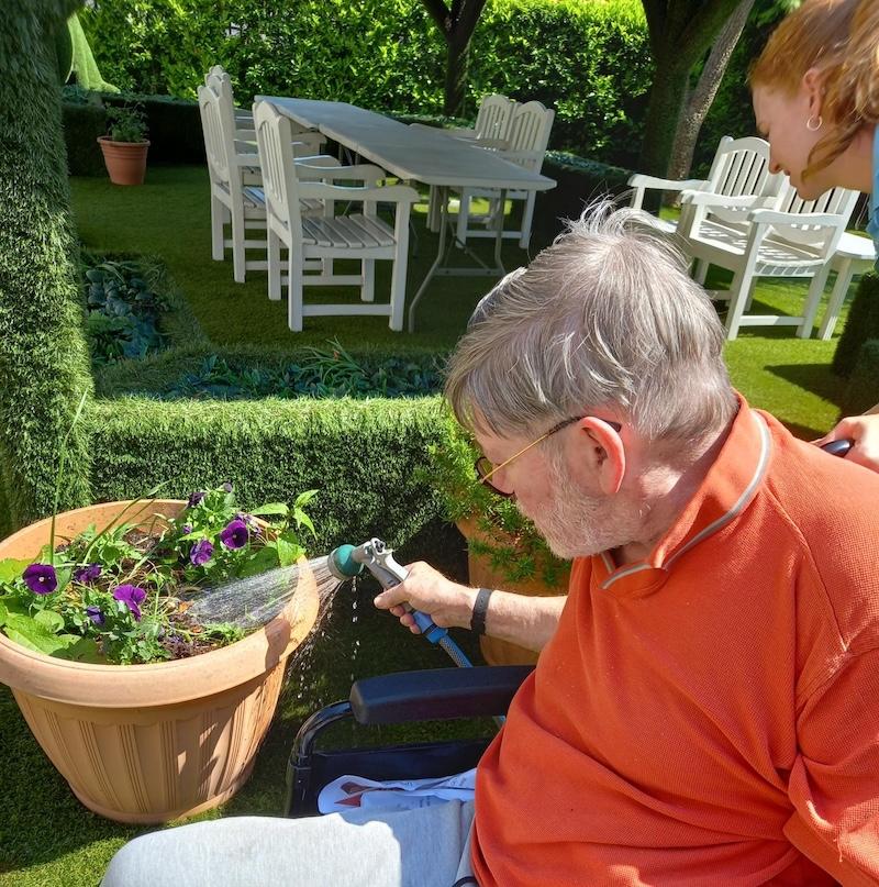 resident sat outside watering the plants with a hose