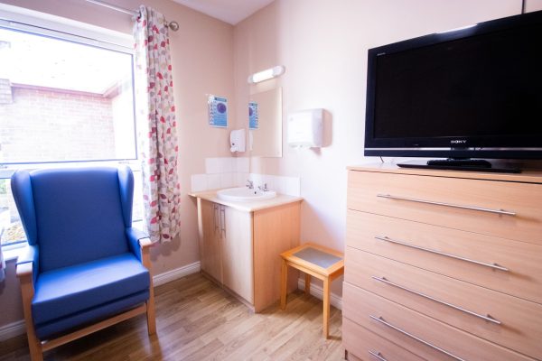 peach room with sink, chair, cabinet and tv
