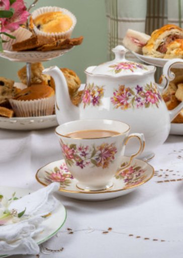 Elegant tea setup with teacup, teapot, and pastries on a table
