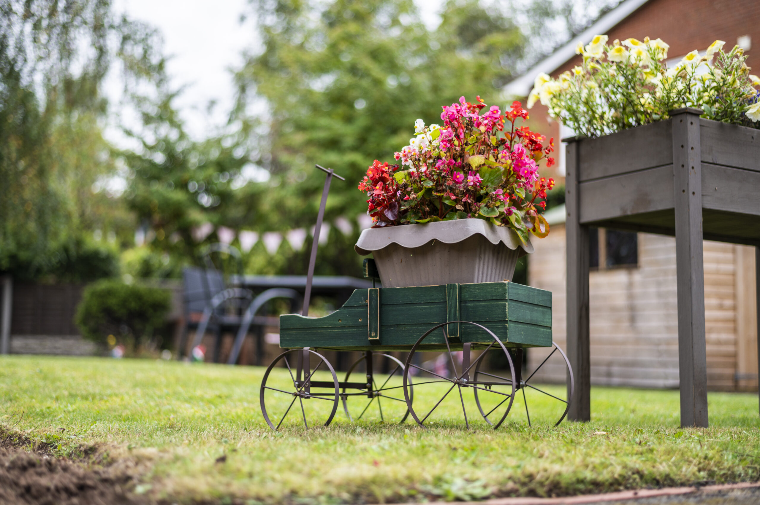 Decorative flower arrangement in a small vintage cart on the lawn at Lucton House care home, with colourful blooms and a garden in the background.