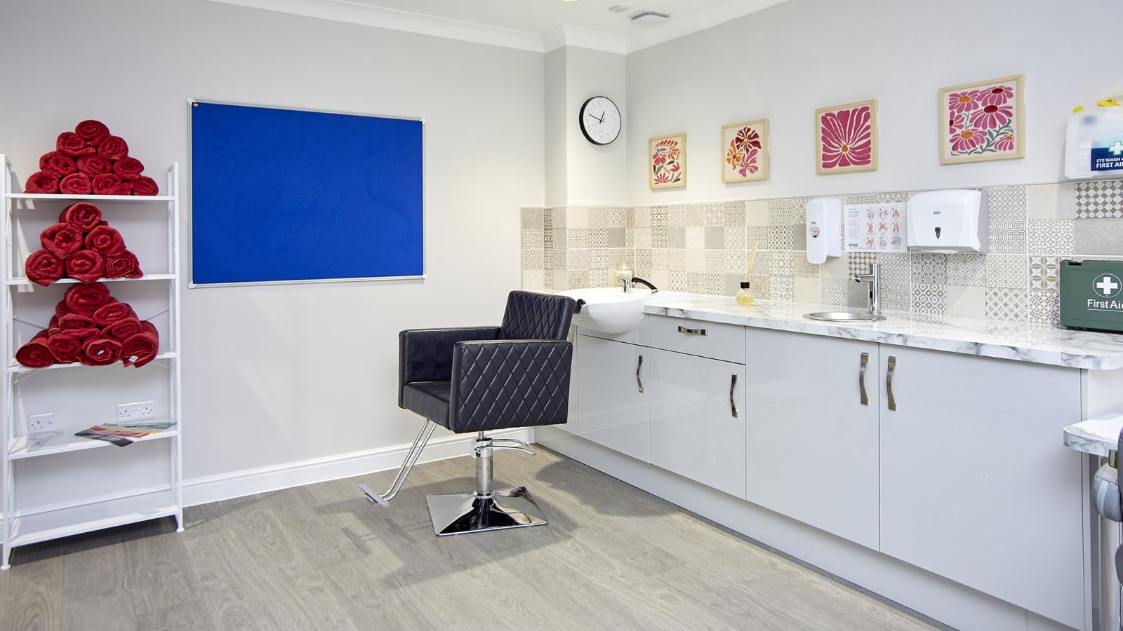 Hair salon with chair, sink and shelves with towels stacked on