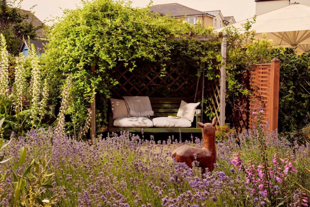 Garden pergola with bench and flowering plants.