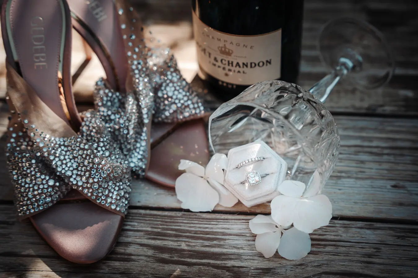 Flatlay mit 2 Brautschuhen, Eheringen, Champagne und Blumen als Deko