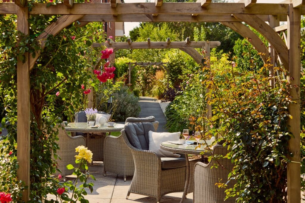 Garden patio with table and chairs under pergola.